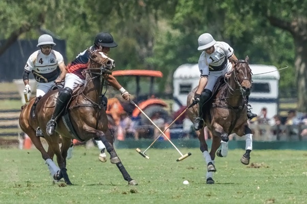 A polo player hooking the mallet of a opposing player